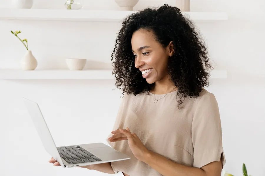 A smiling woman working on a laptop at home