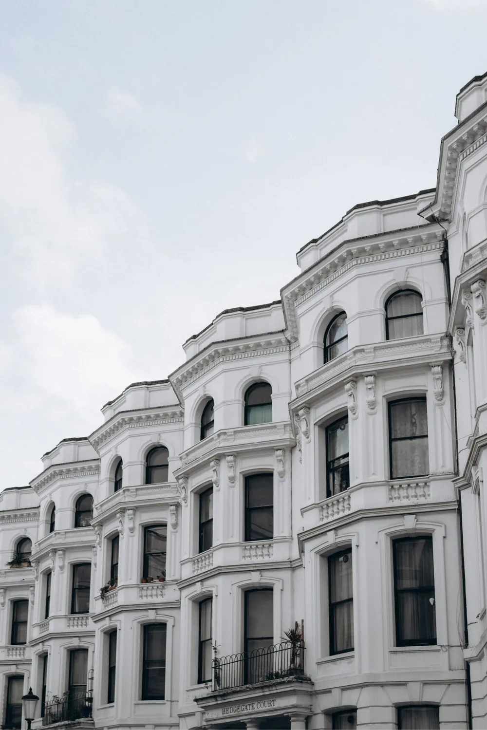 White stucco-fronted Victorian townhouses in London against a pale sky